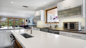 A modern kitchen with a large island, built-in oven, and a large window.