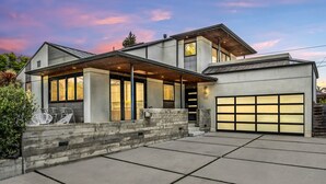 A modern two-story house with a covered patio, large windows, and a garage.
