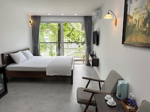 A hotel room with a bed, a desk with a chair, a TV, and a window with curtains. - Hotel Home (Ho Chi Minh City)