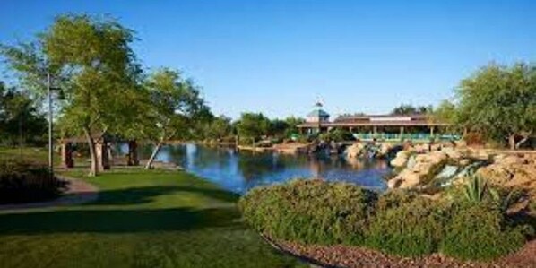 Enjoy a peaceful golfing experience amidst lush greenery and a serene pond.
