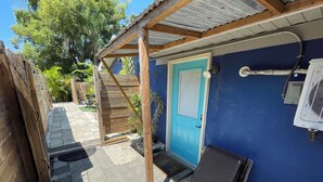 A covered outdoor area with a blue door, a wooden structure, and an air conditioning unit. -     Private Tropical Oasis in Coastal Paradise
W fenced yard. (Clearwater)