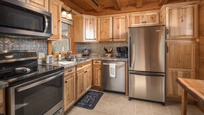 Una cocina moderna con armarios de madera, electrodomésticos de acero inoxidable y encimera negra.