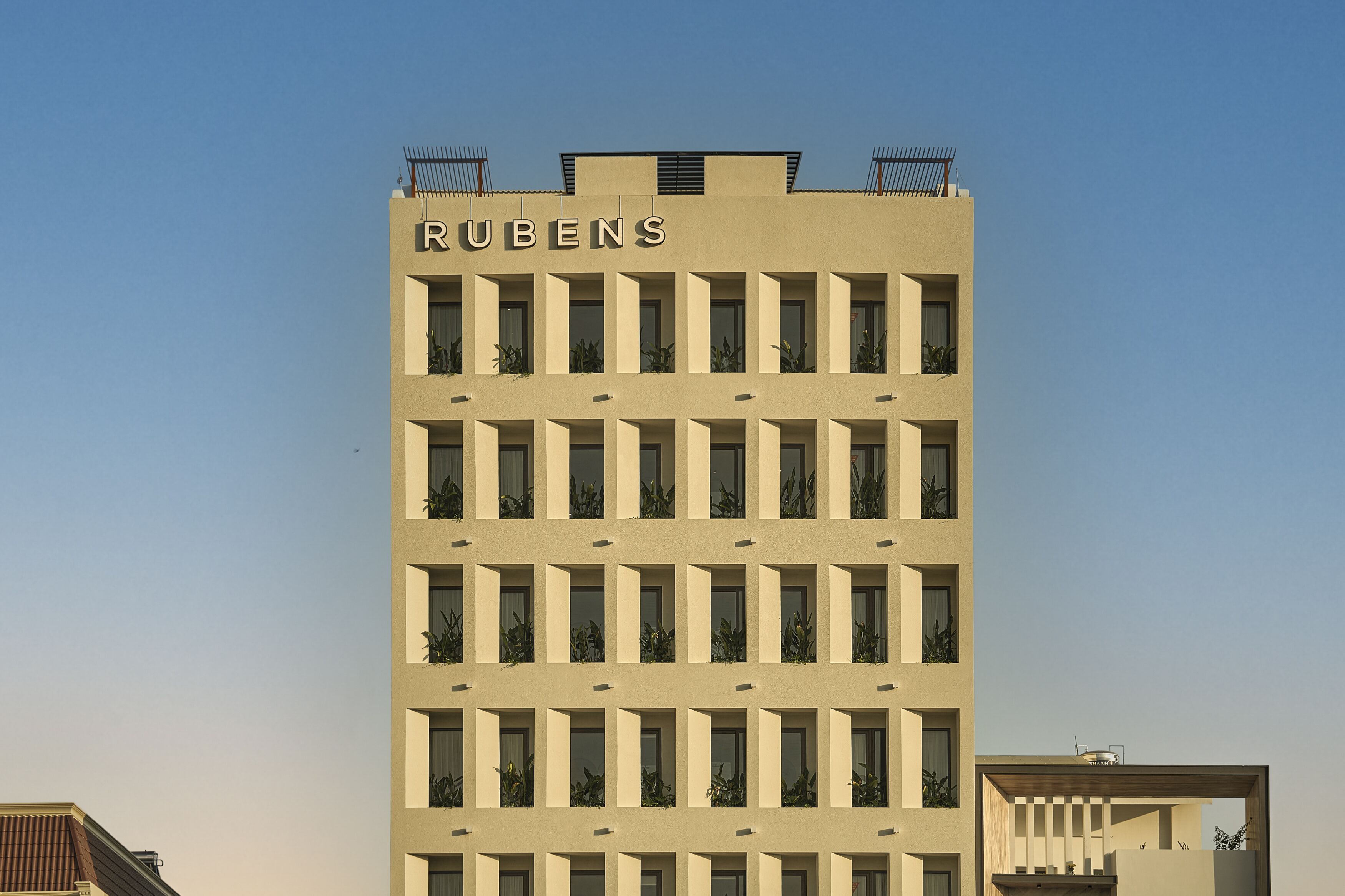 A tall building with the name "RUBENS" on the facade. It has multiple windows and balconies with plants.