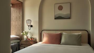 Une chambre à coucher avec un lit, une table de chevet, une lampe et une œuvre d’art accrochée au mur.