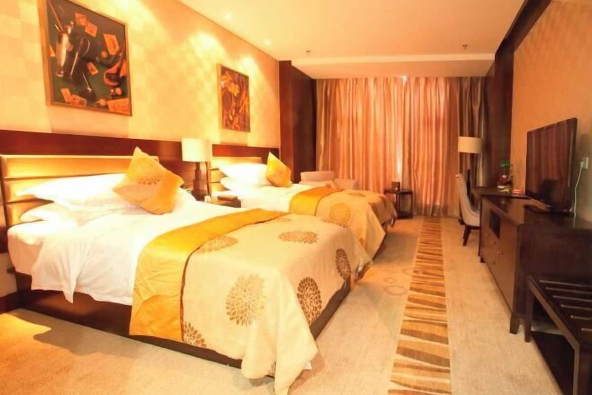 Habitación de hotel con una cama grande, un escritorio, un televisor y un cuadro en la pared.