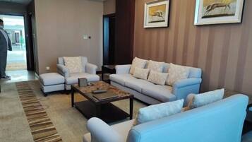 A modern living room with a light blue sofa, a matching armchair, and a coffee table. There are two framed pictures on the wall.