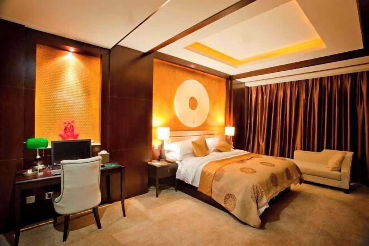Habitación de hotel con cama, escritorio con ordenador, silla y sofá.