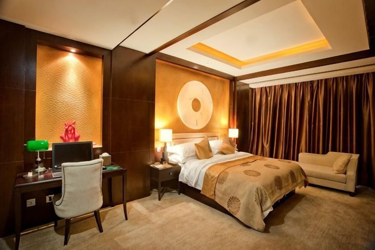 Une chambre d’hôtel comprenant un lit, un bureau, une chaise, un canapé et un mur orné d’un motif circulaire.