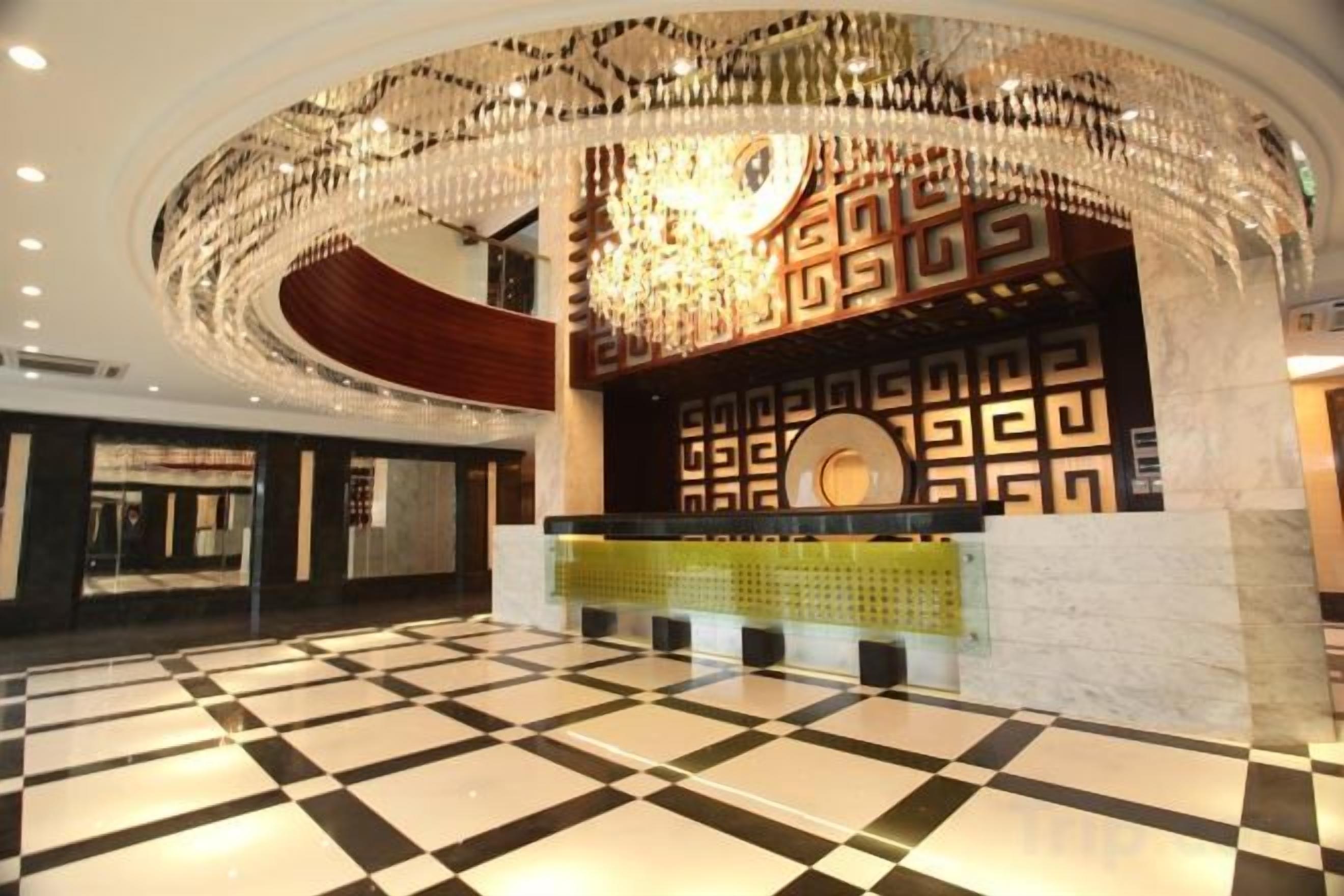 A lobby with a checkered floor, a reception desk, and a decorative wall with geometric patterns.
