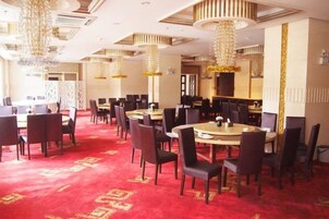 Un comedor de hotel con mesas redondas, sillas y candelabros.