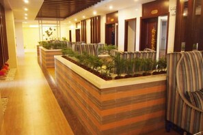 Een hotel lobby met een receptiebalie, een zithoek en een bloemenarrangement.