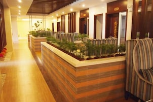 Un vestíbulo de hotel con mostrador de recepción, zona de estar y arreglos de plantas.