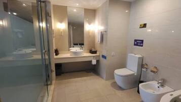 A modern bathroom with a glass shower enclosure, a sink, a toilet, and a bidet.