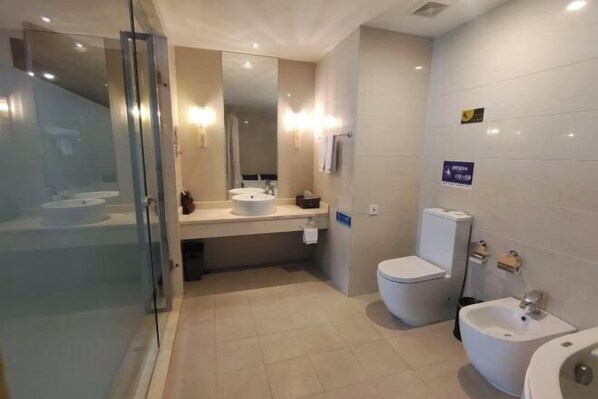 Un baño moderno con cabina de ducha de vidrio, lavamanos, inodoro y bidé.