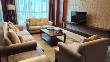 A modern living room with a sofa set, a coffee table, a TV, and patterned wallpaper.