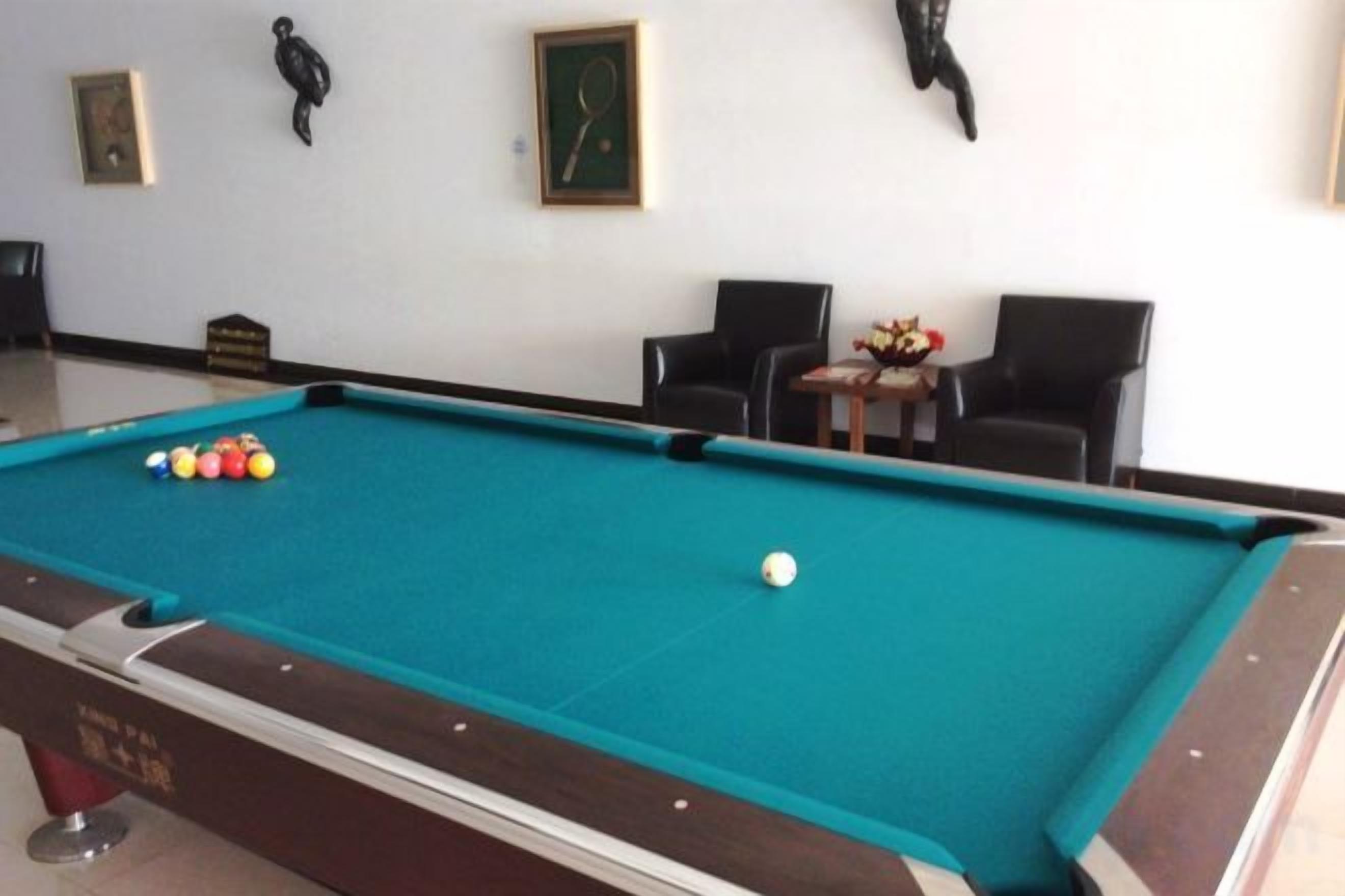Una mesa de billar con bolas, una silla y una mesa con flores.
