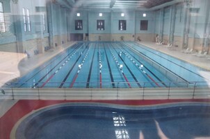Una piscina interior con múltiples carriles, una plataforma de salto y una zona para espectadores.