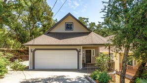A single-story house with a garage, surrounded by trees and a wooden fence.