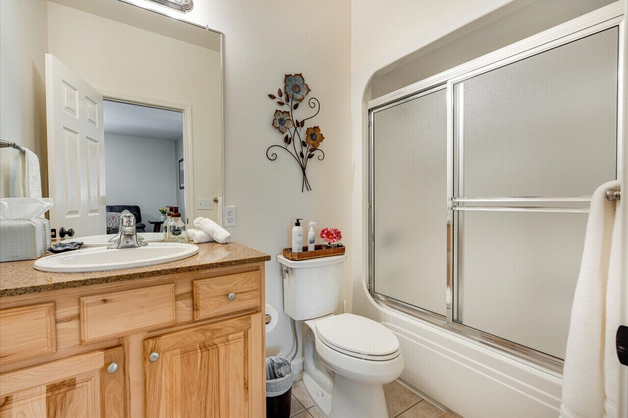 A bathroom with a wooden vanity, white sink, and toilet.