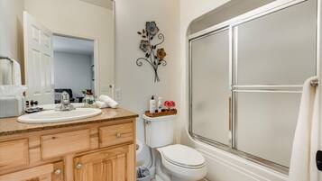 A bathroom with a wooden vanity, white sink, and toilet.