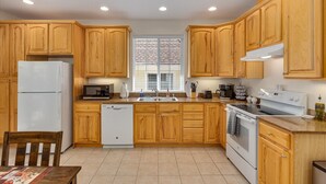A kitchen with wooden cabinets, a refrigerator, a dishwasher, a microwave, a stove, and a sink.