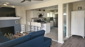 Un salon moderne avec un canapé bleu, une cheminée et un ventilateur de plafond.