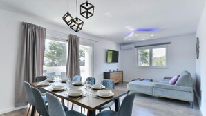Een moderne eetruimte met een houten tafel voor vier personen, grijs beklede stoelen en een modern hanglamp.
