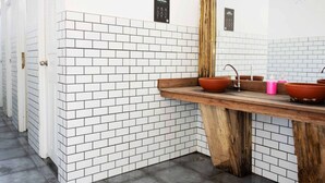A bathroom with white tiled walls, a wooden vanity, and a mirror.