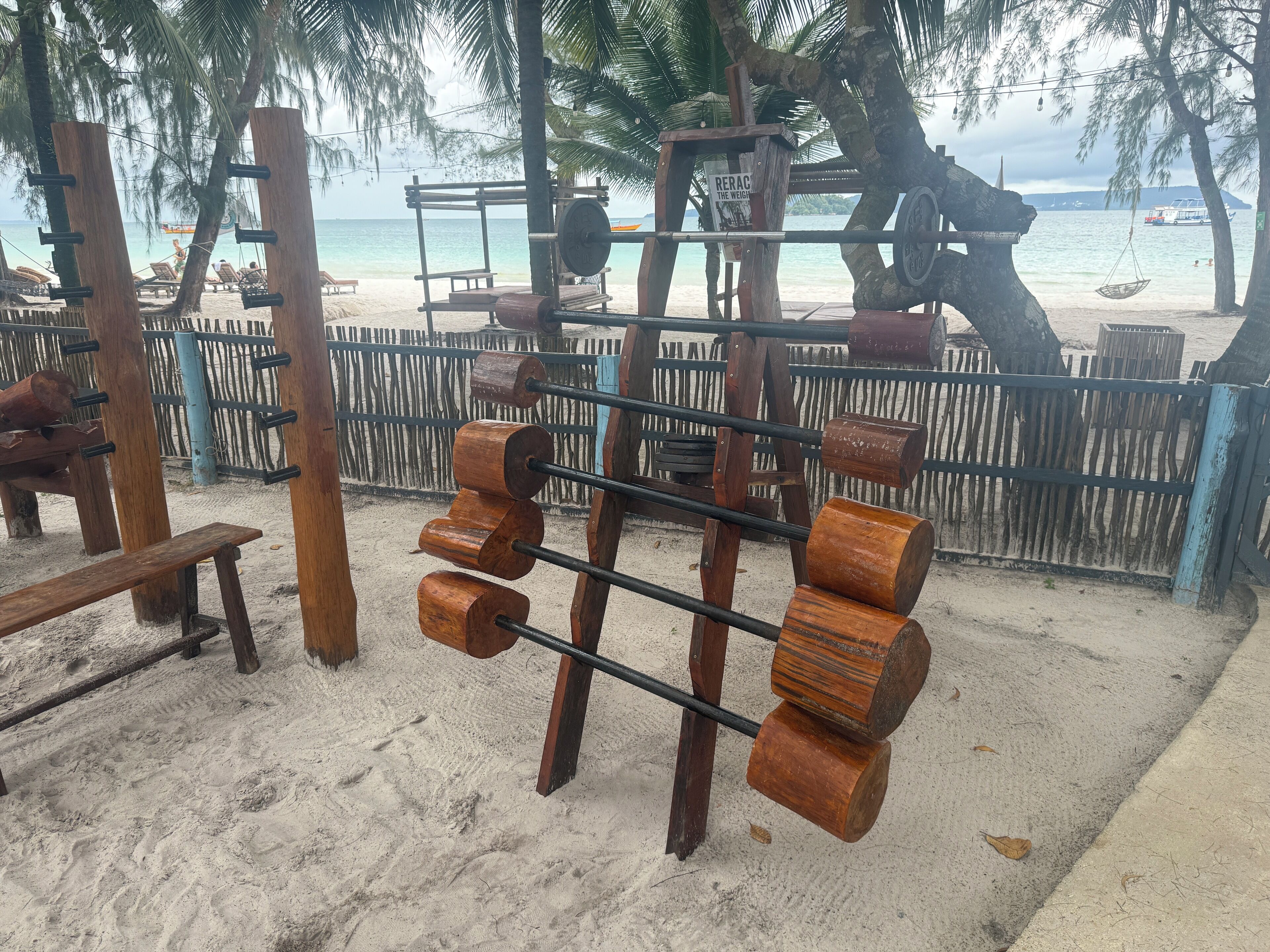 A beachside wooden structure with a swing and a bench.
