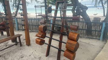 A beachside wooden structure with a swing and a bench.