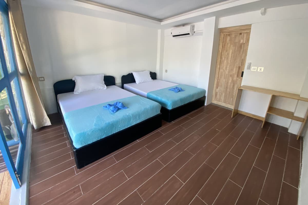 A hotel room with two beds, a wooden wardrobe, and a built-in shelf unit.