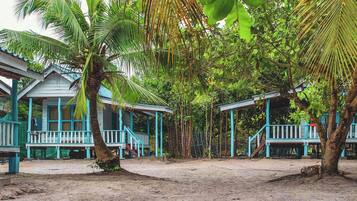 A series of blue-roofed structures with verandas, surrounded by dense tropical foliage.