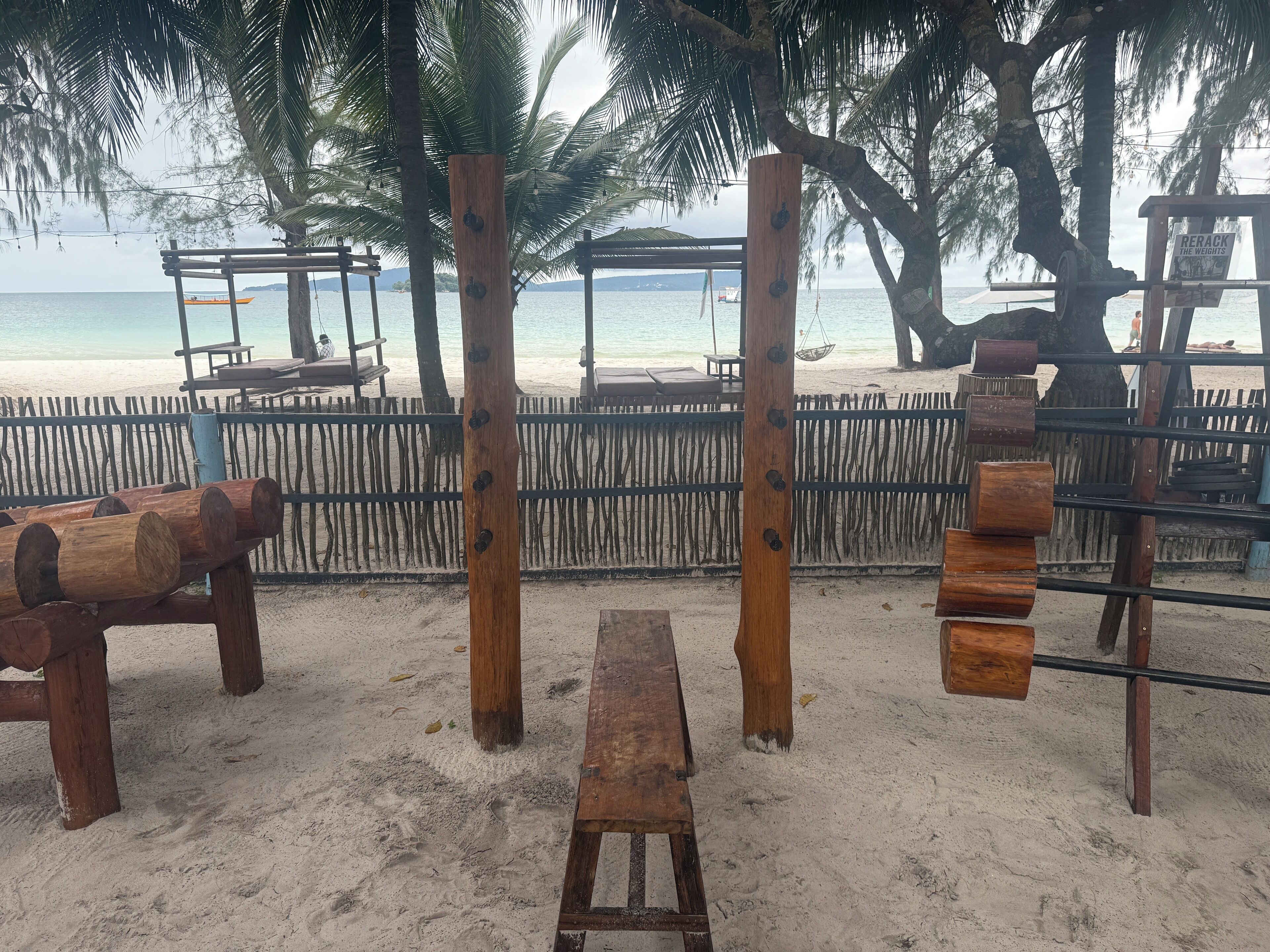A beachside wooden structure with benches and a swing set.