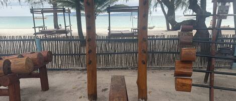 A beachside wooden structure with benches and a swing set.