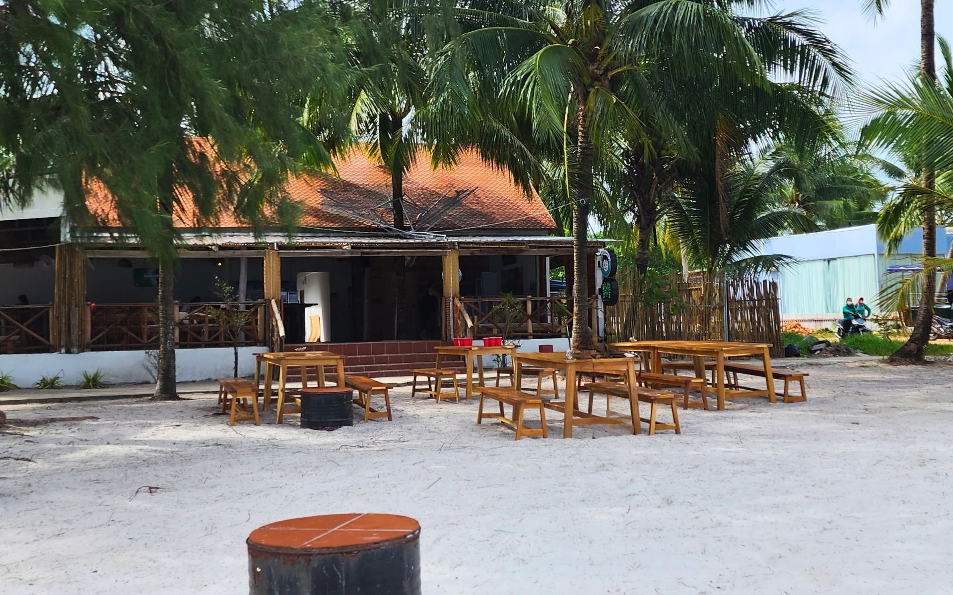 A beachside restaurant with outdoor seating and palm trees.