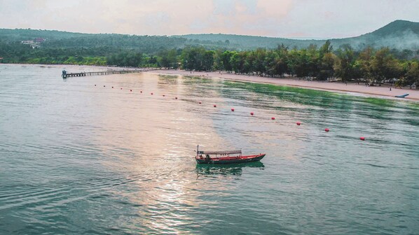 A boat on calm water with a pier and trees in the background. - Mad Monkey Koh Rong (Koh Rong)