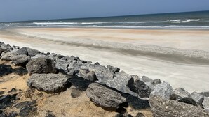 Une plage avec un rivage rocheux au premier plan et des vagues à l’arrière-plan.