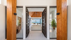 A modern entrance with wooden pillars, a glass door, and a view of a cozy living area with a sofa and a plant.
