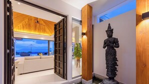 A modern interior with a wooden ceiling, a Buddha statue, and a view of the outdoors.