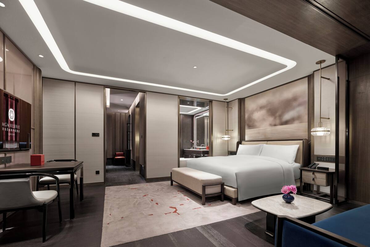 Una habitación de hotel moderna con una cama grande, mesitas de noche, un escritorio y una zona de estar.