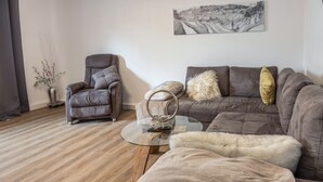 A living room with a sofa, armchair, and glass coffee table.