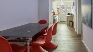 A modern kitchen with a dining area featuring a dark table and red chairs.