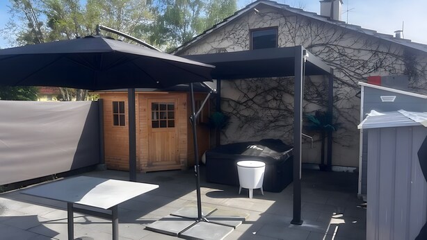 A patio area with a table, a barbecue grill, and a wooden shed.