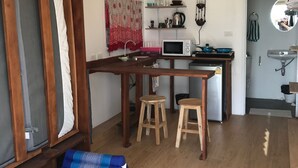 A compact living space with a kitchenette, a dining area, and a seating area with a sofa and stools. - Walden Koh Lanta Tiny Homes by the Sea (Ko Lanta)