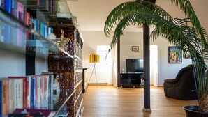 A living room with a bookshelf, a TV, a sofa, and a potted plant.