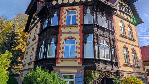 A multi-story building with a traditional architectural style, featuring ornate woodwork and a mix of brick and plaster facades.