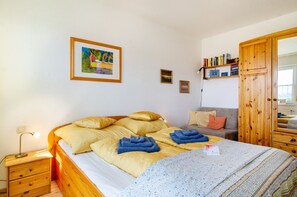 Une pièce comprenant un lit, une table de chevet, une armoire en bois, un canapé et un mur orné de tableaux.