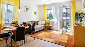 A modern living room with a sofa, dining table, chairs, and a small side table with a vase.