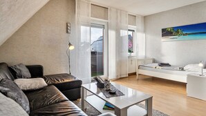Un salon moderne avec un canapé, une table basse, un lit et un tableau accroché au mur.