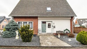 Une maison d’habitation avec un toit en tuiles, une porte d’entrée, une petite fenêtre et une allée gravillonnée.